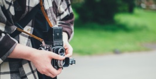 A person holding an old camera taking a photo