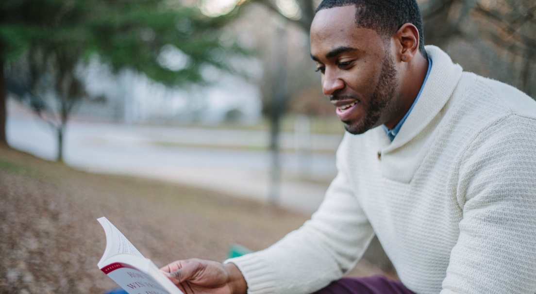Man happily reading book in park